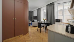 A modern kitchen with a microwave, a kettle, and a dining area with a table and chairs. - Atmospheric Apartment in the New Town | Next to the Barbican (Warszawa)