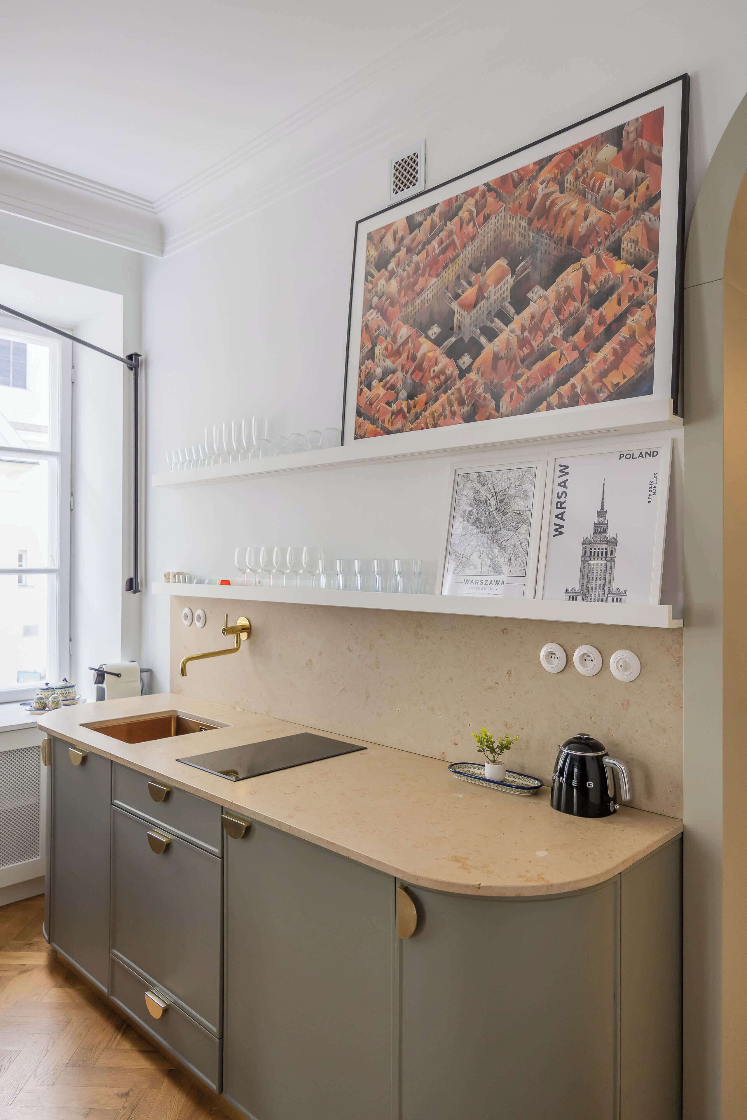 A kitchen with a sink, a coffee maker, and a framed map of Warsaw.