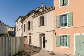 A narrow street with buildings featuring stone facades and green shutters. - Charming 1750 Stonehouse in the heart of Saint Rémy (Saint-Rémy-de-Provence)