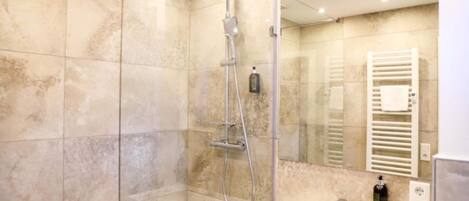 A modern bathroom with a glass-enclosed shower, a white sink, and a mirror.