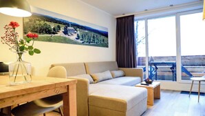 A modern living room with a sofa, a dining table, and a large window with a view of a landscape. - Helles und Modernes Appartement (Winterberg)