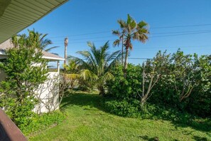 Zona residencial con una casa, palmeras y un patio cubierto de césped.