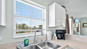 A kitchen with a double sink, a coffee maker, and a window with blinds. - Beachfront Duplex 6BR/4BA – 16+ Guests – Paradise Park, Melbourne FL (Melbourne)