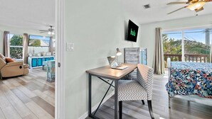 A modern living room with a dining area, a TV mounted on the wall, and a balcony with a view. - Beachfront Duplex 6BR/4BA – 16+ Guests – Paradise Park, Melbourne FL (Melbourne)