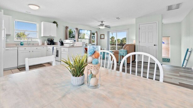 A modern kitchen with white cabinets, a dining table with chairs, and a ceiling fan. - Beachfront Duplex 6BR/4BA – 16+ Guests – Paradise Park, Melbourne FL (Melbourne)