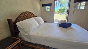 Una cama con ropa de cama blanca, un cabecero de madera y una mesita de noche.
