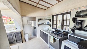 Una cocina compacta equipada con refrigerador, estufa, lavamanos y ventana.