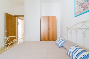 Una camera da letto con un letto, un armadio, una porta e un quadro appeso al muro.