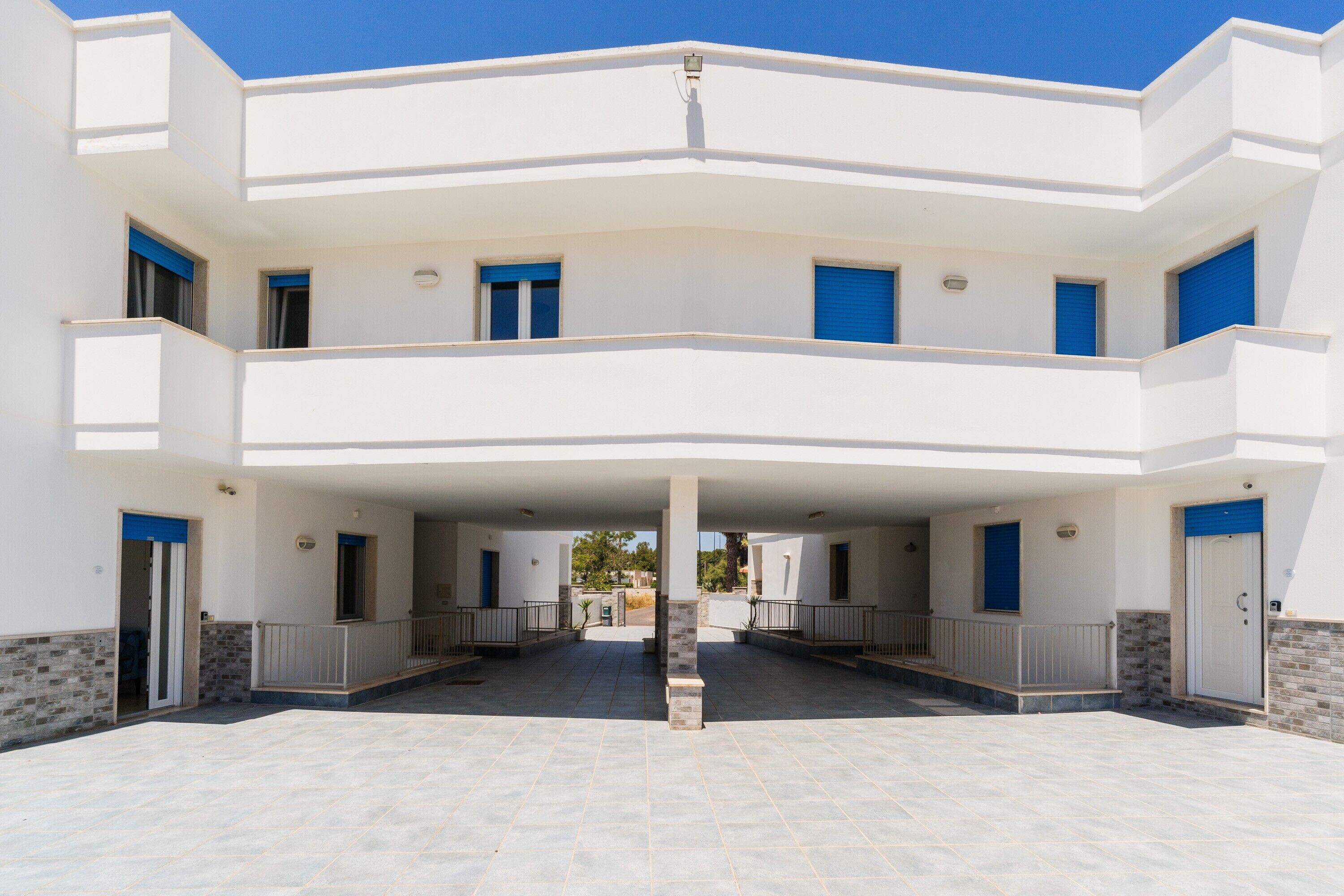 Un edificio a più piani con un cortile interno, balconi e un tetto piano.