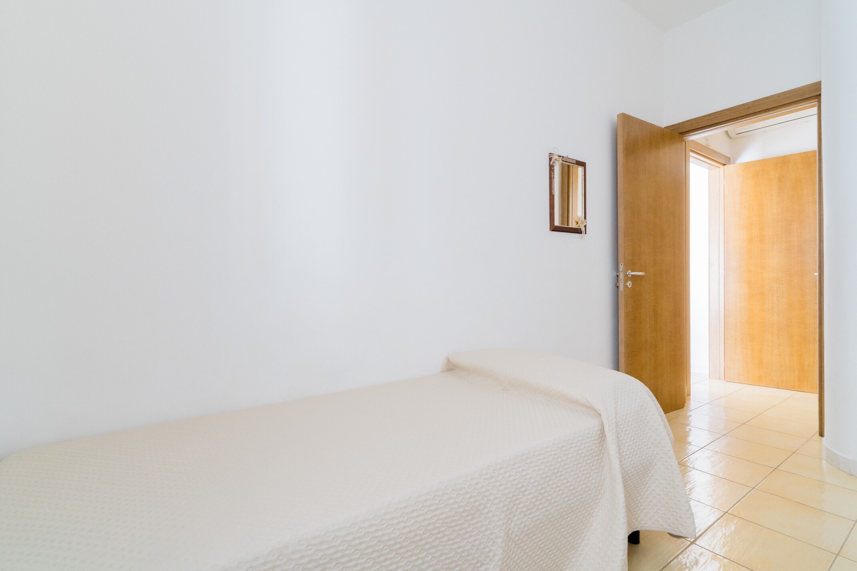 Ein Zimmer mit einem Bett, einer Tür und Blick in ein anderes Zimmer.