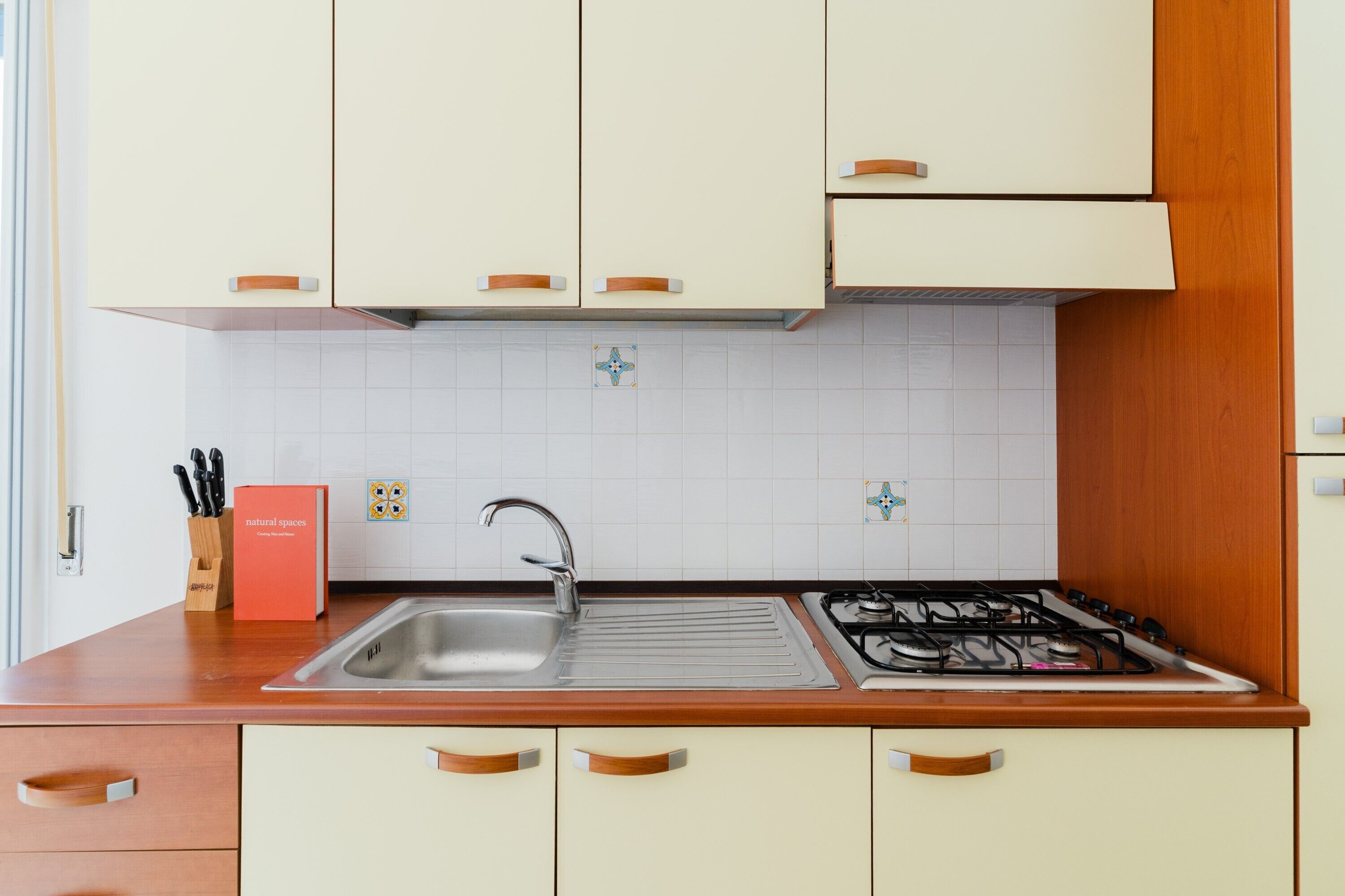 A kitchen with a sink, stove, and cabinets.