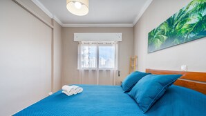 A bedroom with a bed, a window, a painting, and a ceiling light. - Apartment 'Columbia Praia Da Rocha' with Balcony, Wi-Fi, Air Conditioning and garage (Portimão)