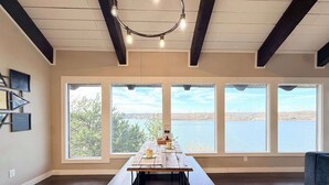 A spacious room with a large table, multiple windows, and a view of a body of water. - Wide Sky Chateau Lake Views (Osage Beach)