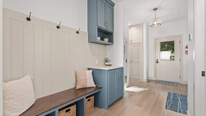 Ein Korridor mit einer Bank, einem blauen Schrank, einer Tür und einer Pendelleuchte.
