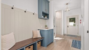 Ein Korridor mit einer Bank, einem blauen Schrank, einer Tür und einer Pendelleuchte.