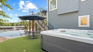 Ett bubbelbadkar bredvid ett hus med en uteplats och utsikt över en sjö.