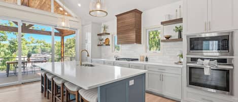 Una cocina moderna con una isla grande, electrodomésticos de acero inoxidable y vistas al exterior.