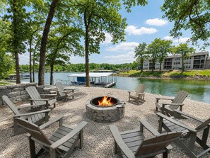 Ein Sitzbereich im Freien am Seeufer mit Adirondack-Stühlen und einem Steinkamin.