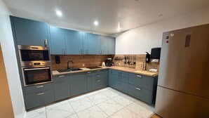 Une cuisine moderne avec des meubles gris, un four en acier inoxydable, un évier et un plan de travail en bois.