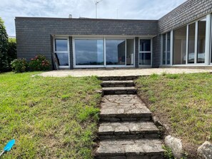 Un edificio moderno con fachada de ladrillo, grandes puertas de vidrio y una escalera de piedra que lleva a la entrada.