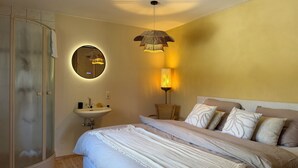 Une chambre à coucher avec un lit, un miroir rond, une lampe de chevet, un plancher en bois et une étagère fixée au mur.