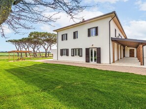 Une maison moderne à deux étages, dotée d’un patio couvert, d’une pelouse bien entretenue et offrant une vue sur la campagne.