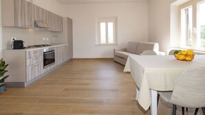 Una cocina moderna con comedor, sofá y una mesa con frutero.