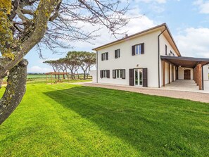 A modern two-story house with a covered patio, a well-maintained lawn, and a view of the countryside. - Apartment I Pini by Interhome (Bibbona)