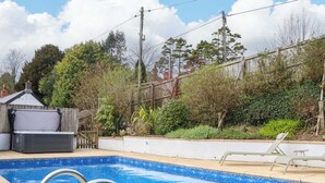 Een zwembad met houten terras, een ligstoel en een jacuzzi.