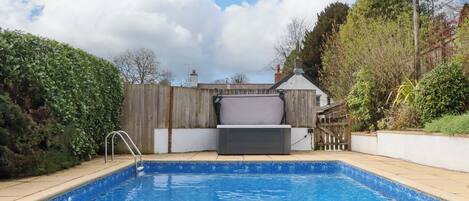A swimming pool with a wooden deck, a metal ladder, and a white fence.