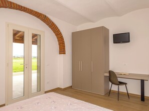 Un dormitorio con cama, escritorio, silla, armario y televisor.
