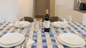 A dining table set with plates, glasses, and a bottle of wine, with a checkered tablecloth. - Apartment I Pini by Interhome (Bibbona)