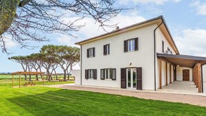 Una moderna casa a due piani con portico coperto, un prato curato e vista sulla campagna.