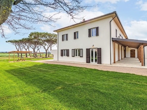 A modern two-story house with a covered patio, a well-maintained lawn, and a view of the countryside. - Apartment I Pini by Interhome (Bibbona)
