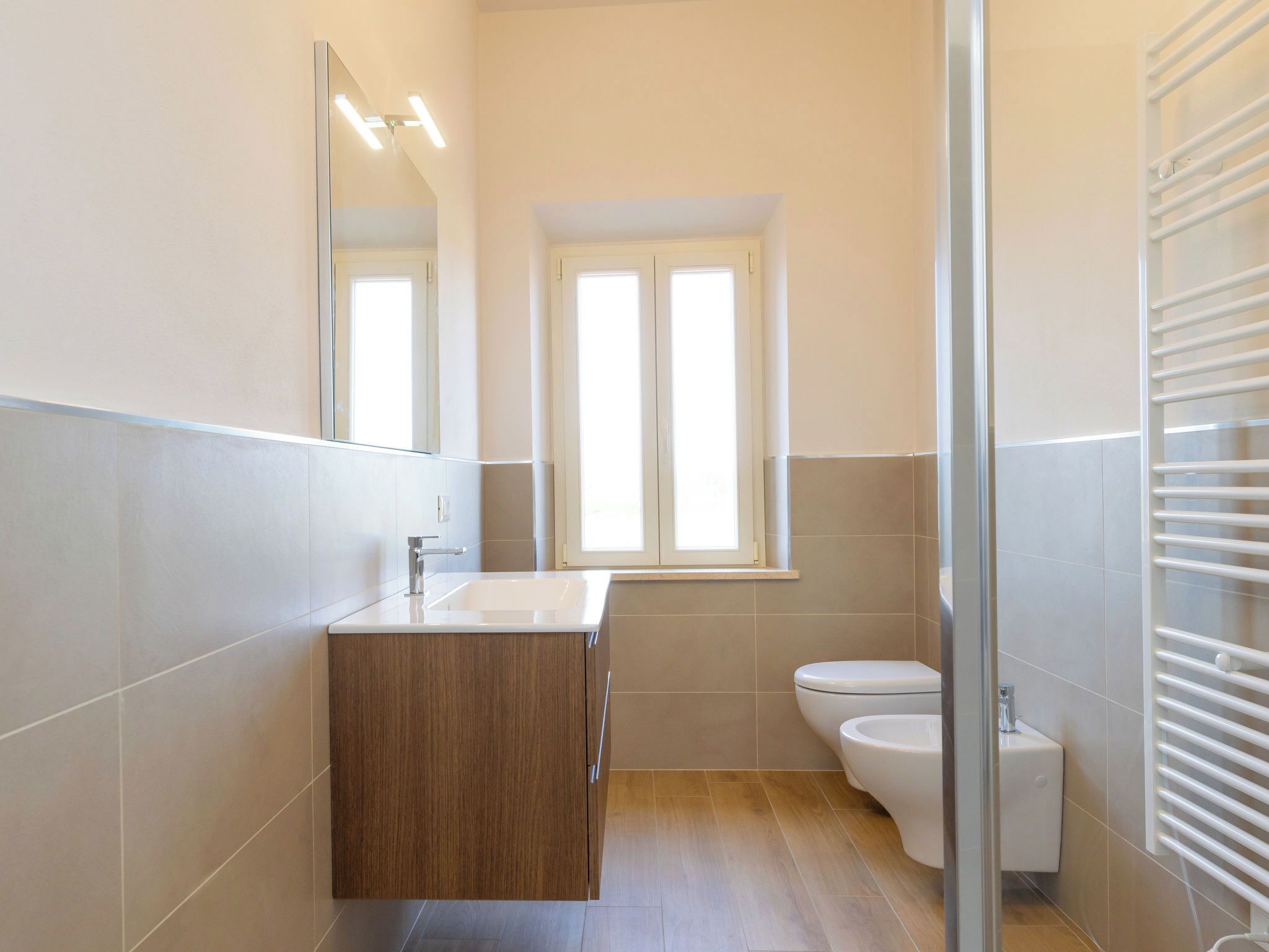 Un baño moderno con tocador de madera, inodoro y cabina de ducha de vidrio.