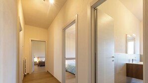 Un corridoio che porta a una camera da letto con un letto, un bagno con un lavandino e uno specchio.