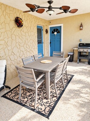 A patio with a table and chairs, a ceiling fan, a blue door, and a barbecue grill. - 🌴🍹Rustic Coastal Retreat with Patio, BBQ, & Privacy Fenced Yard! Near Beaches! (Sebastian)