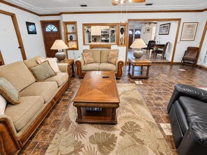 A living room with a sofa, a coffee table, and a dining area with chairs. - 🌴🍹Rustic Coastal Retreat with Patio, BBQ, & Privacy Fenced Yard! Near Beaches! (Sebastian)
