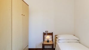 A small room with a single bed, a wooden chair with a lamp, and a wardrobe. - Casa Pradell by Interhome (Gravedona)