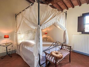 A four-poster canopy bed with a bench beside it, a small table with a lamp, and a radiator. - di Alica by Interhome (Palaia)
