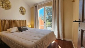 Un dormitorio con cama, mesita de noche, lámpara, ventana con cortinas y decoración en la pared.