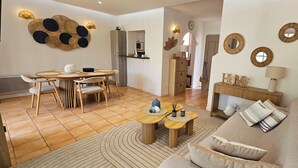 Una sala de estar moderna con una mesa redonda de comedor, un sofá y una cocina al fondo.
