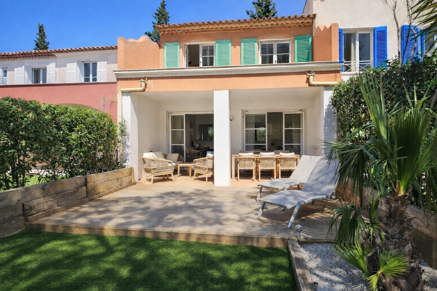 Une maison avec un patio, du mobilier d’extérieur et un jardin.