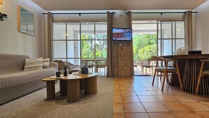 Una sala de estar con sofá, mesa de centro, televisión y comedor con sillas y mesa.
