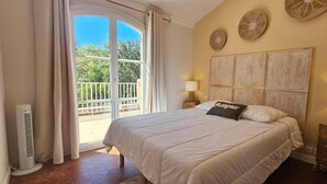 Un dormitorio con una cama grande, un balcón con cortinas, un calentador y decoración en la pared.