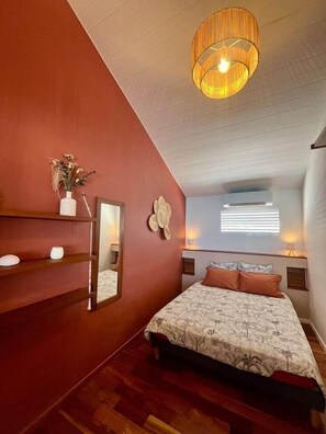 A bedroom with a bed, a mirror, a vase with dried flowers, and a ceiling light fixture. - Apartment KayTi palm trees (Sainte-Luce)