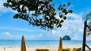 Ein Tisch am Strand mit Stühlen, einem Getränk und einer Mahlzeit.