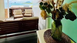 Ein Zimmer mit Meerblick, ein Korbwäscher mit Blumen und eine hölzerne Bank.