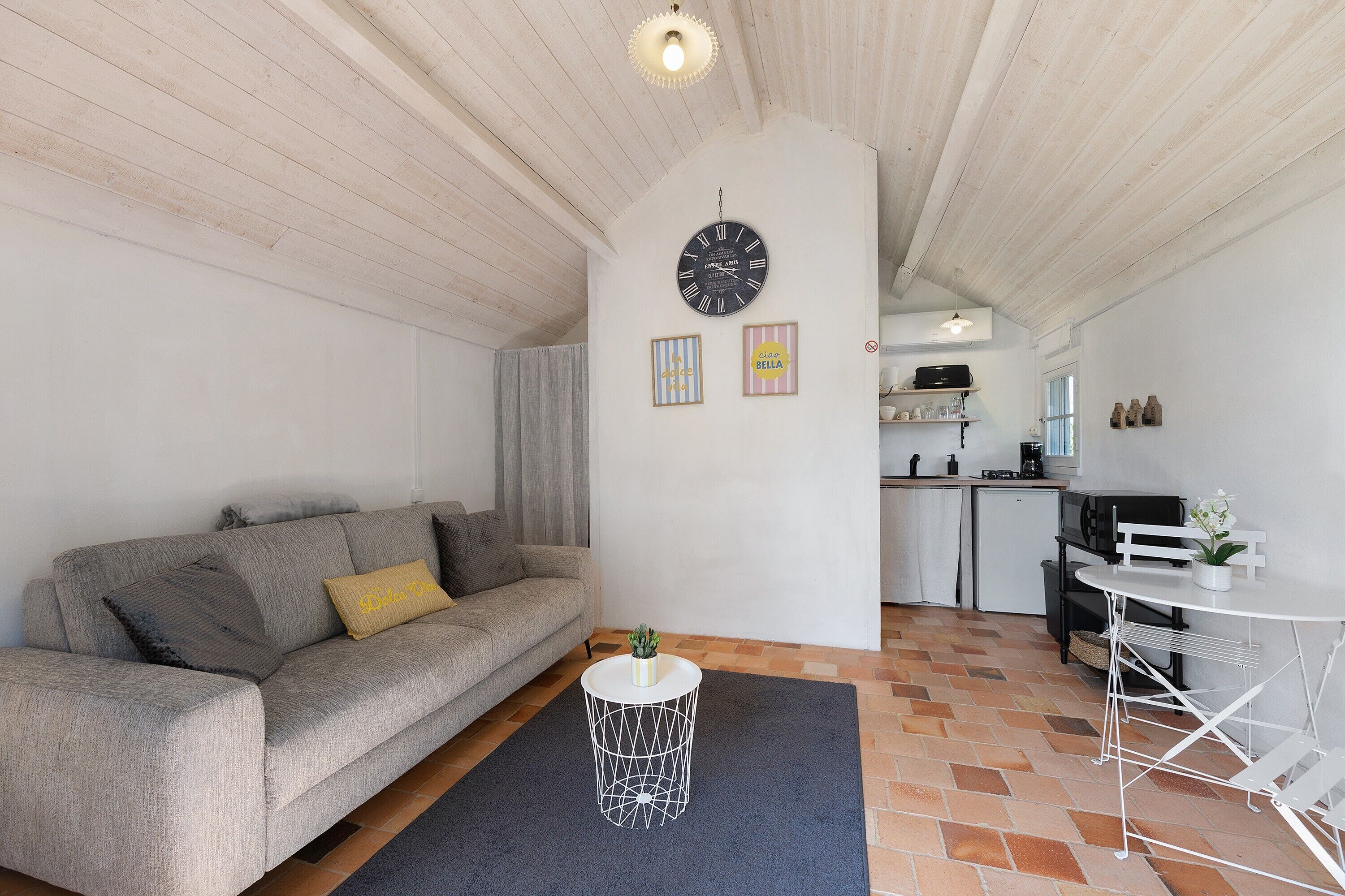 A modern living room with a sofa, a round coffee table, a kitchen area, and a dining table.