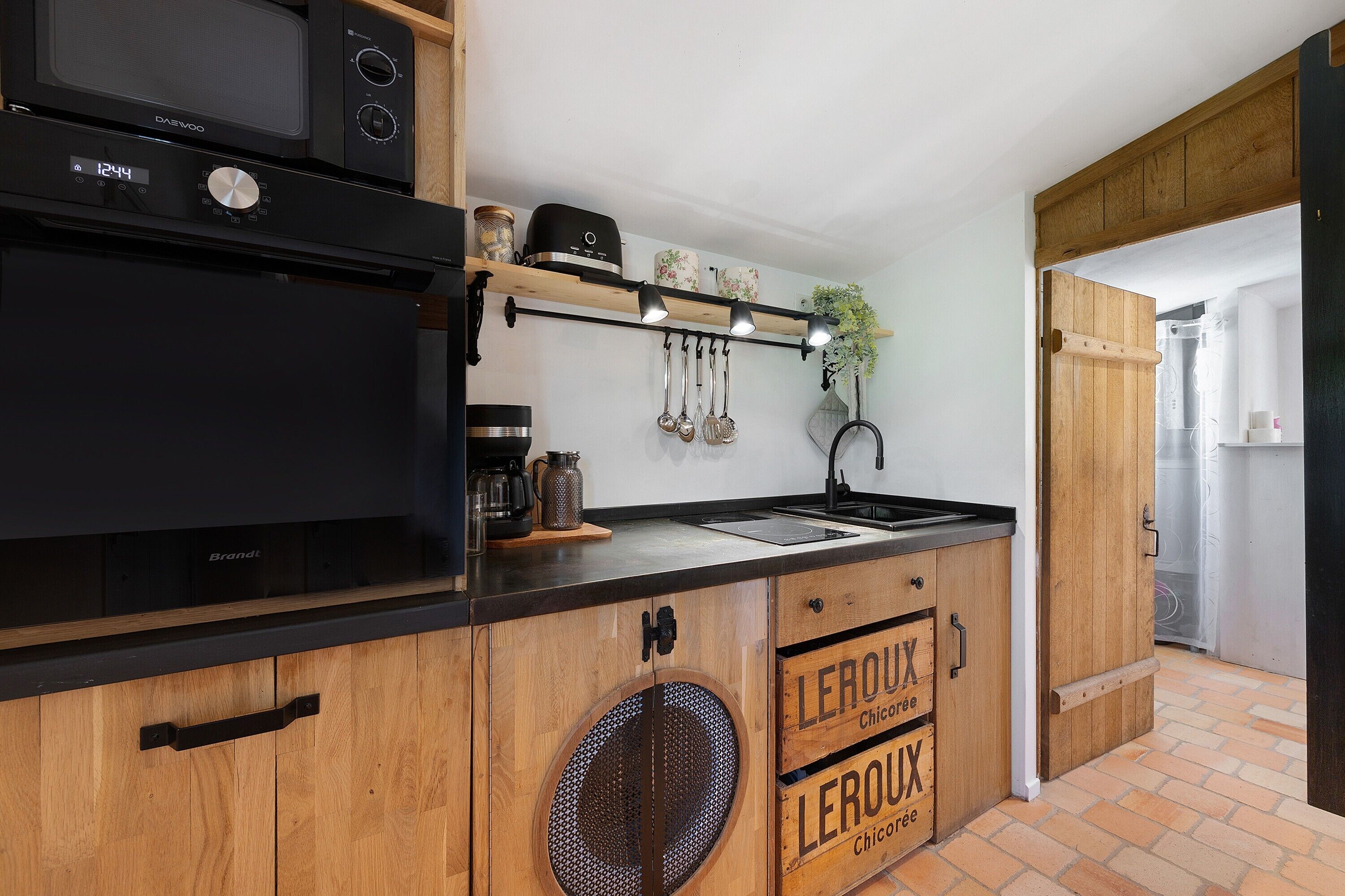 Une cuisine équipée d’un four à micro-ondes, d’une machine à café et de meubles de rangement en bois.